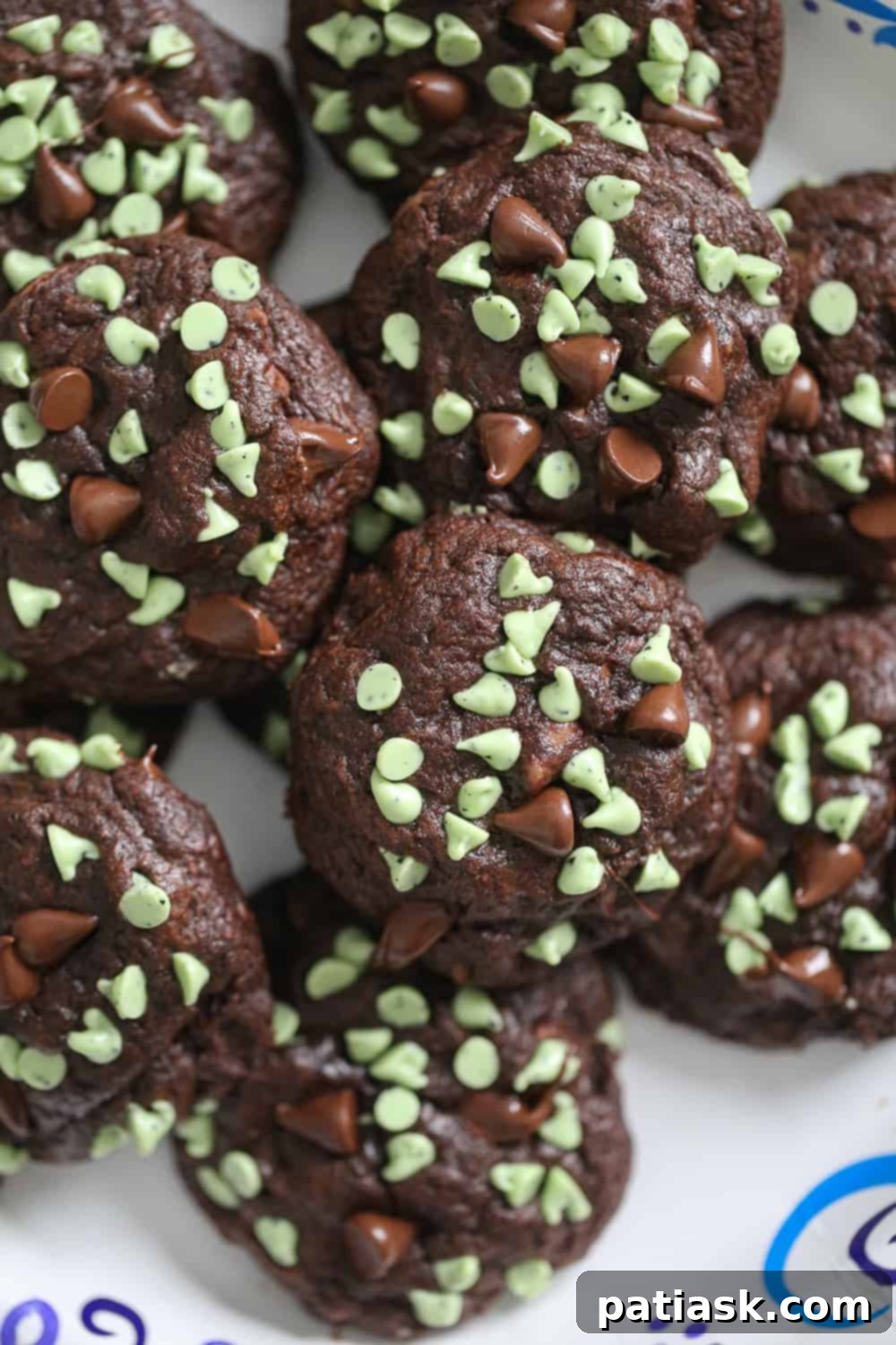 Irresistible Soft Batch Chocolate Mint Chip Cookies 4 A close-up image of two Soft Batch Chocolate Mint Chip Cookies on a plate, highlighting their soft centers.