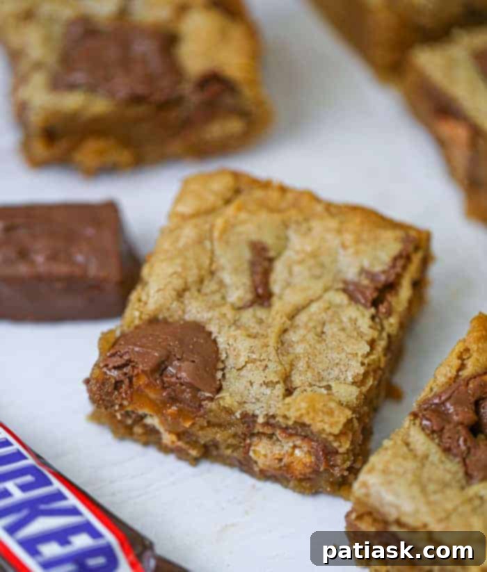 Heavenly Snickers Peanut Butter Blondies 3 Close-up of a perfectly baked Snickers Peanut Butter Blondie, showcasing its fudgy interior and candy chunks.