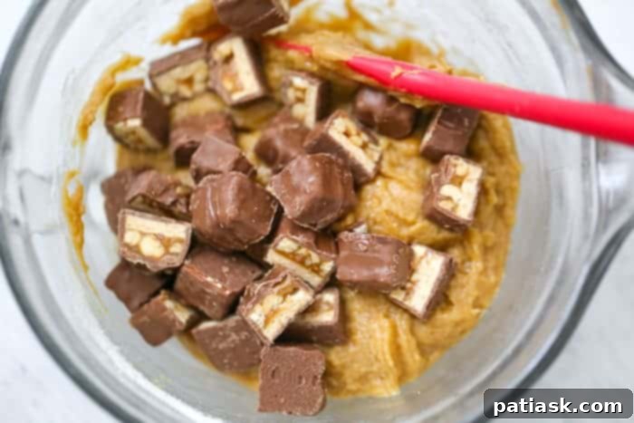 Heavenly Snickers Peanut Butter Blondies 5 Close-up of three Snickers Peanut Butter Blondies, showing the gooey caramel and peanut chunks.