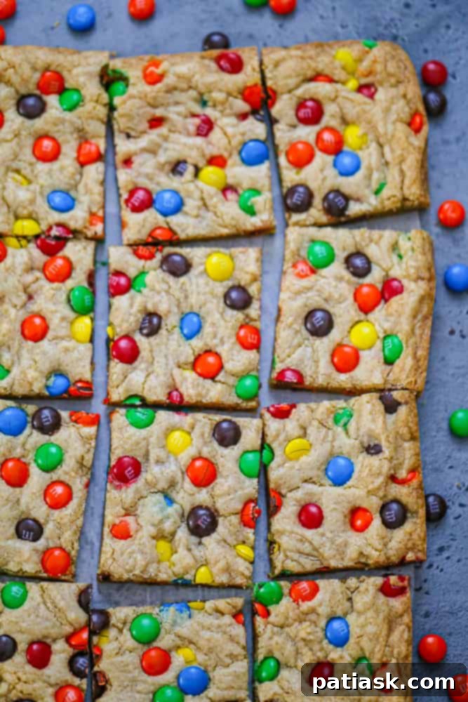 A delicious square of M&M Cookie Bar on a wooden board