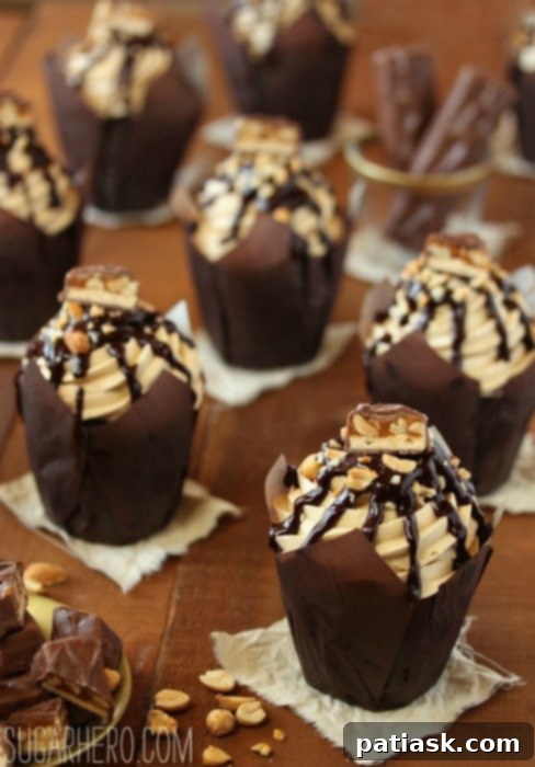 Decadent Snickers Cupcakes with peanut caramel filling, peanut butter frosting, and chocolate toppings.