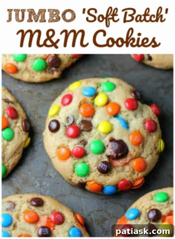 A close-up shot of a single Jumbo Soft Batch M&M Cookie, revealing its perfectly golden edges, soft center, and abundance of colorful M&Ms.