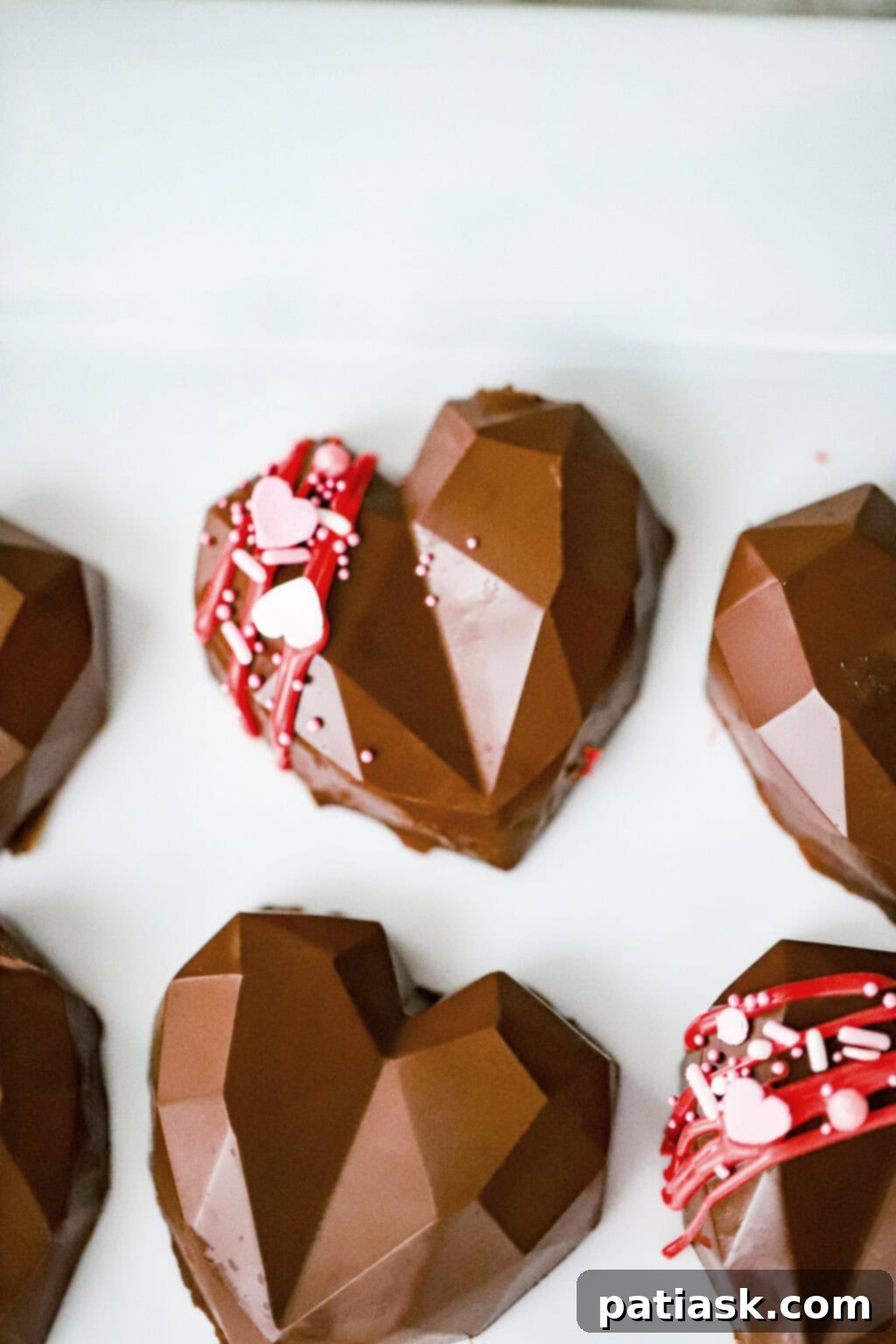 Homemade peanut butter cup hearts with silicone molds in the background, showcasing the simplicity of the process